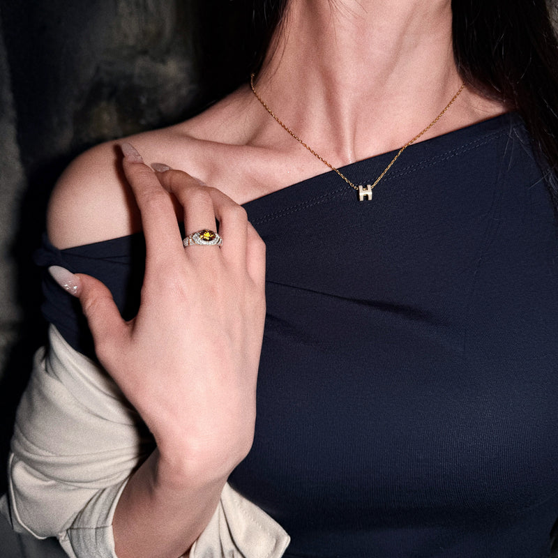 AUREL yellow east-west oval gemstone pav¨¦ ring worn on a hand resting near the shoulder, with a black top.