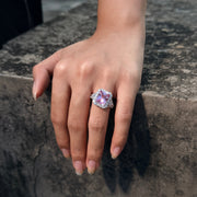 REINE pink radiant-cut halo ring shown on a hand resting on stone
