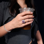 REINE radiant-cut pink gemstone ring styled with black clothing while holding a drink