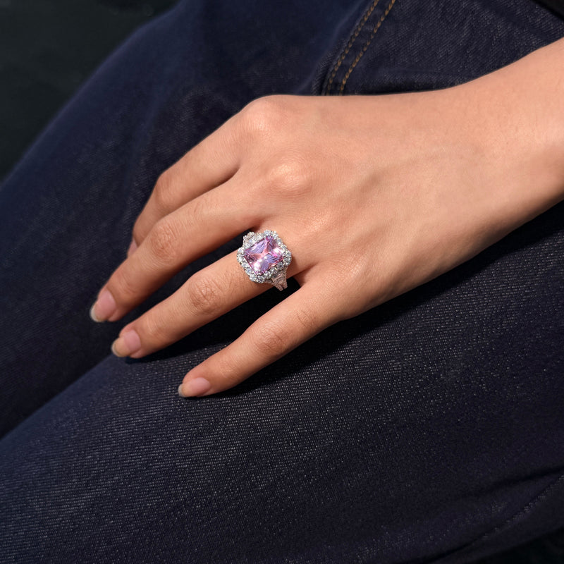 REINE pink gemstone halo ring shown on a hand against dark denim