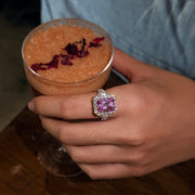 REINE pink gemstone halo ring shown beside a glass of fruit tea