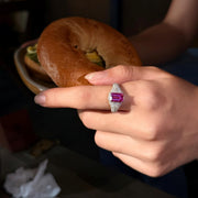 VAREN emerald-cut pink gemstone ring worn on a hand holding a sandwich