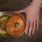 VAREN pink gemstone cocktail ring shown on a hand resting beside a plate