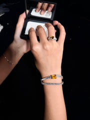 AUREL yellow gemstone ring worn while holding a compact mirror