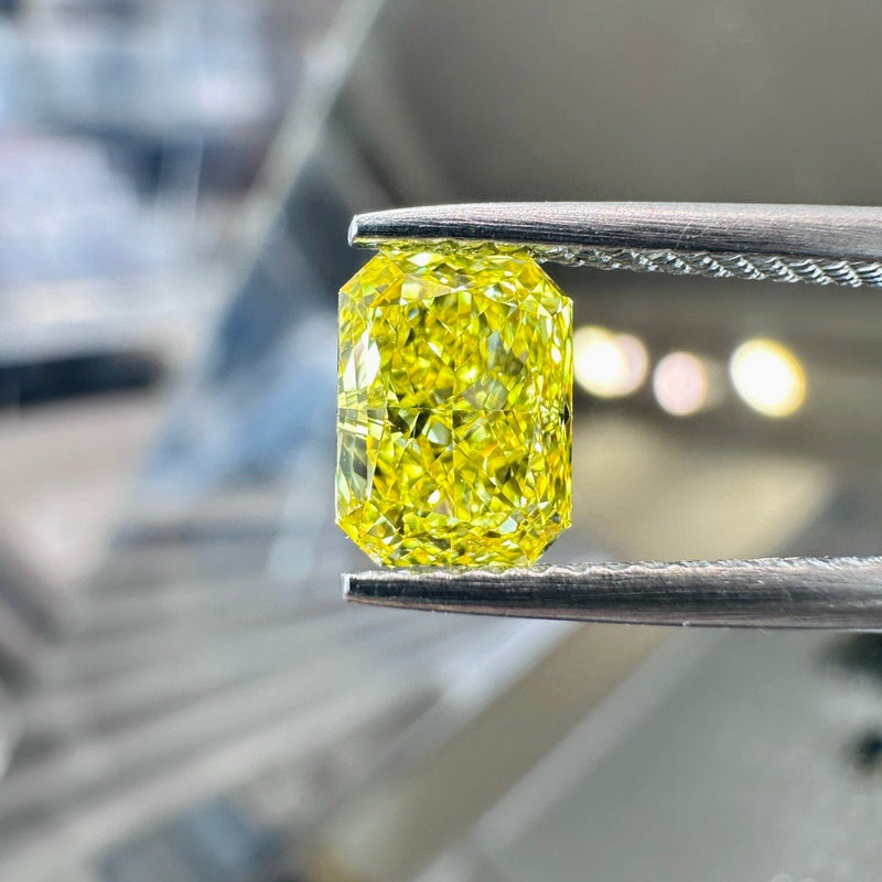 Actual photograph of the 1.01 ct Fancy Vivid Yellow SI1 radiant-cut lab-grown diamond held in tweezers.