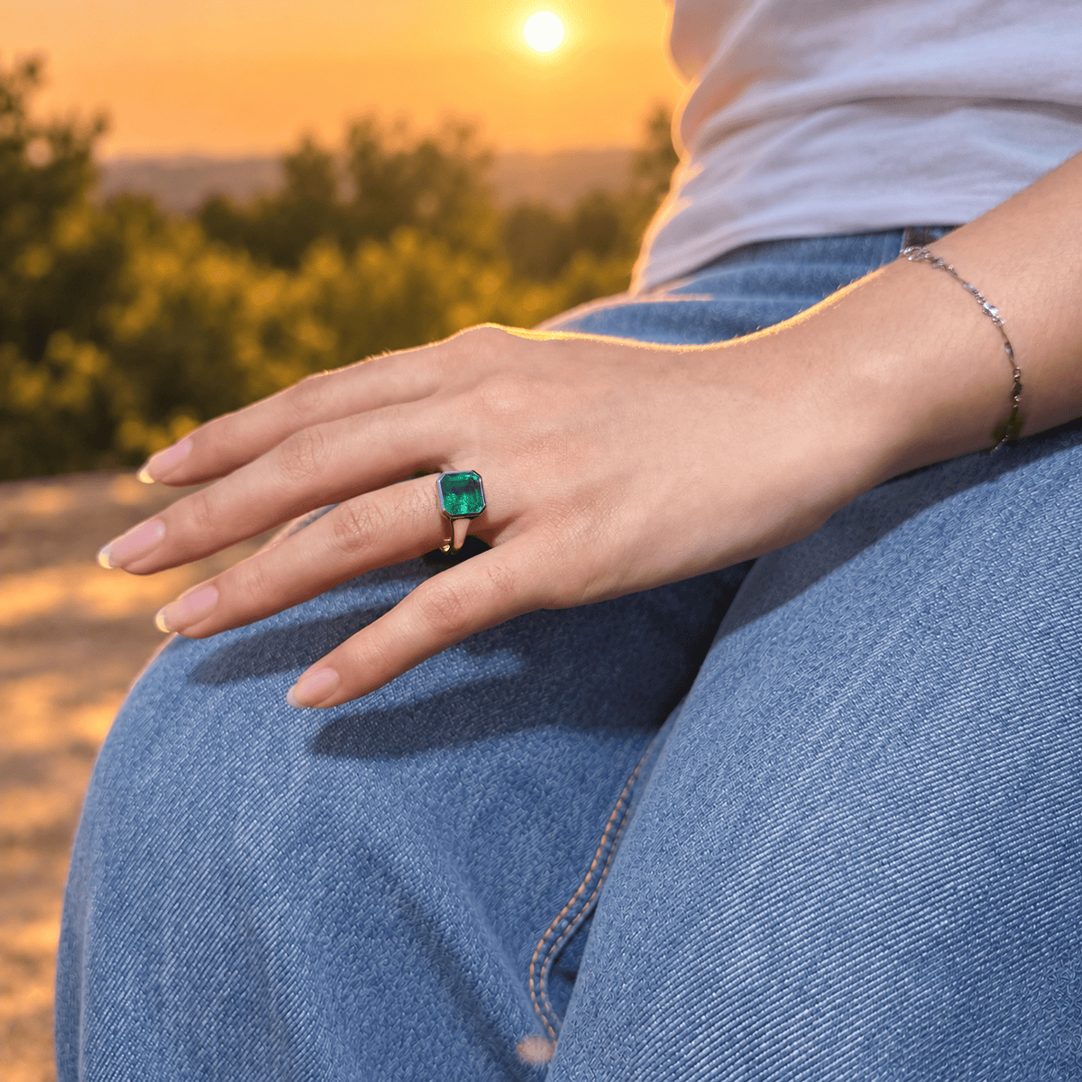 NOA green lab-grown emerald signet ring worn on a hand resting on denim