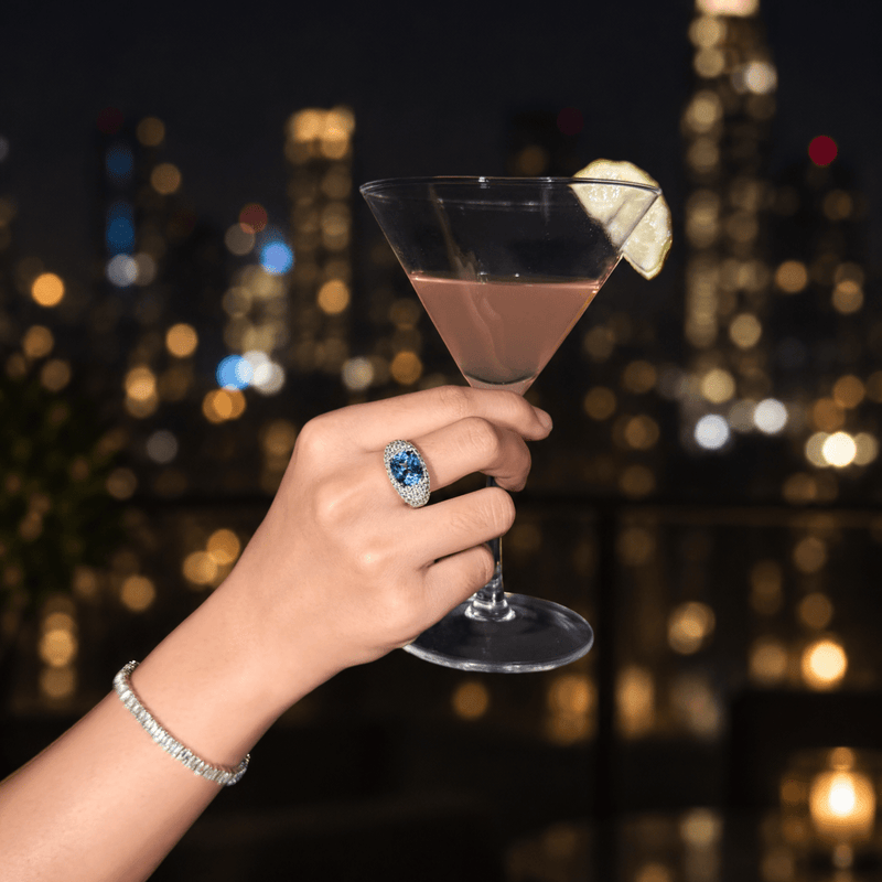 ORBE blue gemstone pav¨¦ cocktail ring worn on a hand holding a cocktail glass