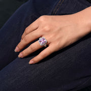 REINE pink gemstone halo ring shown on a hand against dark denim