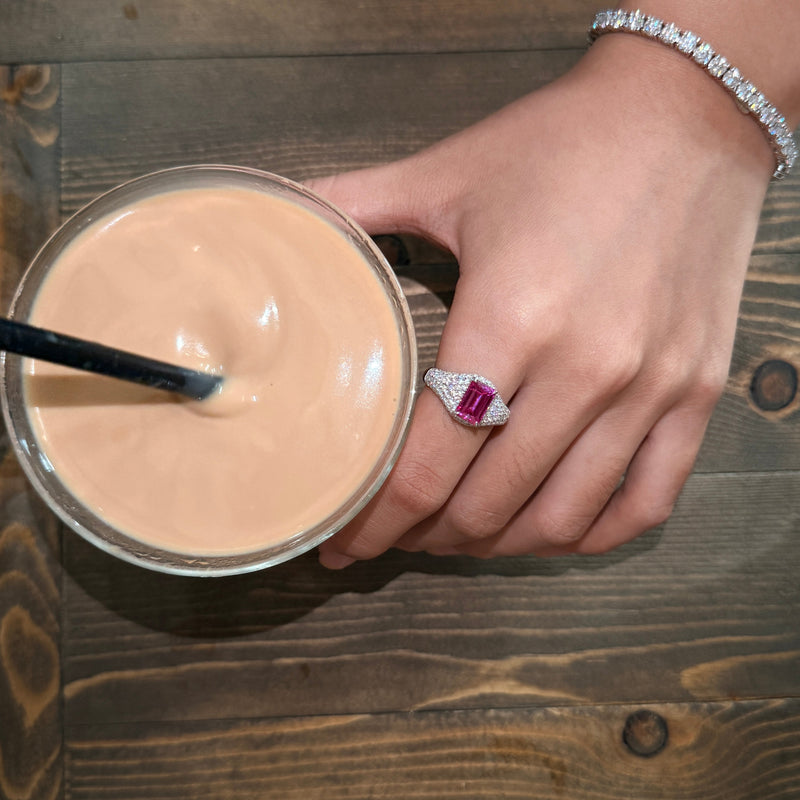 VAREN pink emerald-cut cocktail ring shown beside a glass of iced coffee